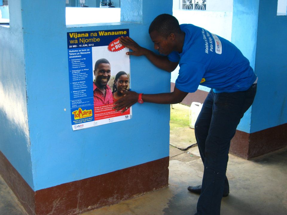 A health worker puts up a poster in a health facility.