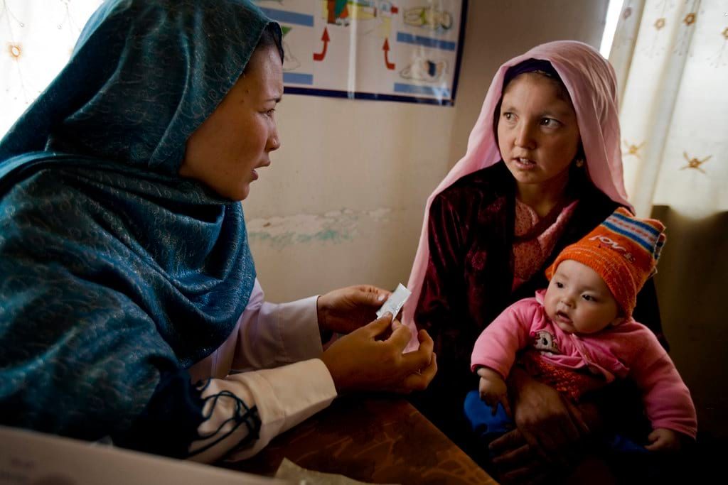 Midwife discussing family planning options with a woman holding a baby.