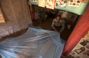 A CHV demonstrates a method to hang a mosquito net over a bed by supporting it with chairs.