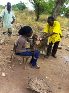 Two men standing and one woman sitting and holding baby