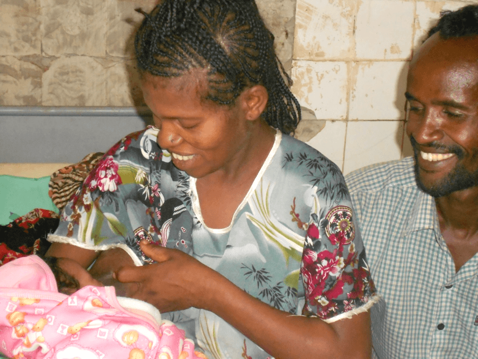 Woman and man smiling and holding baby