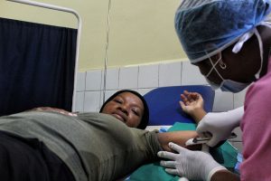 Woman laying on table getting implant inserted by midwife