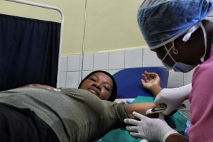 Woman laying on table getting implant inserted by midwife