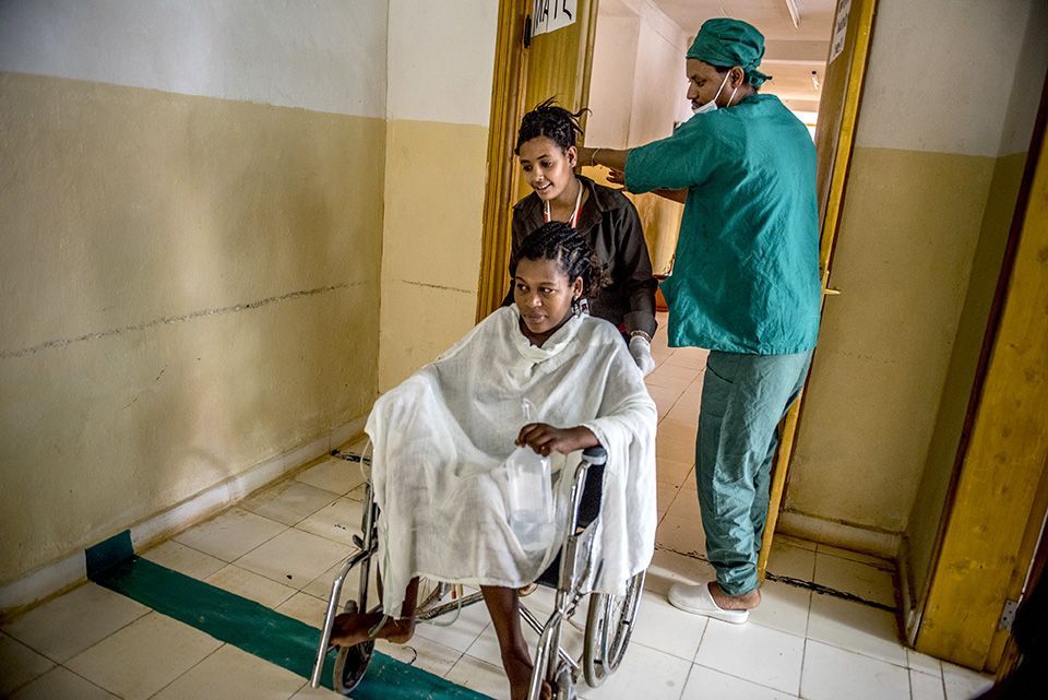 Woman being pushed in wheelchair by man and woman