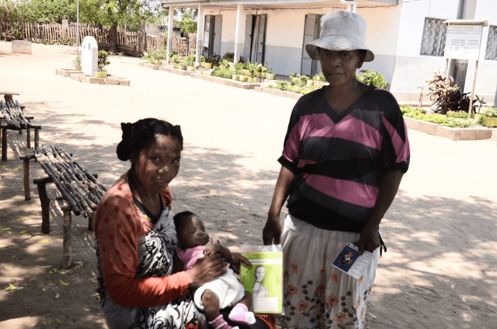 Woman sitting and holding baby next to standing woman