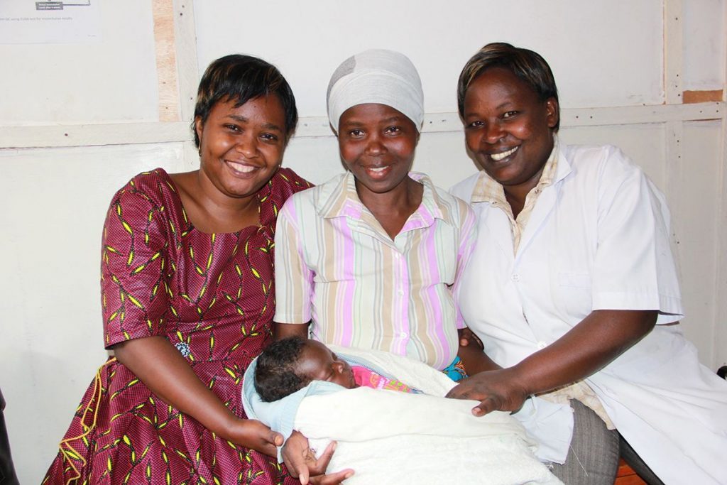 Three women smiling and holding a baby