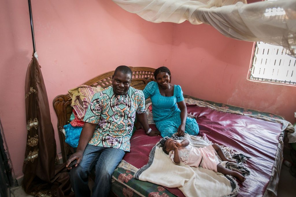 man, woman and child sitting on bed