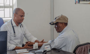 Two men sitting, one holding the other's forearm