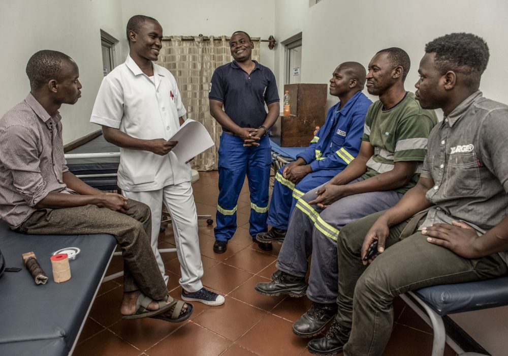 Male nurse speaking with a group of men at a health clinic.