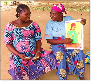 Two women sitting, one holding illustration