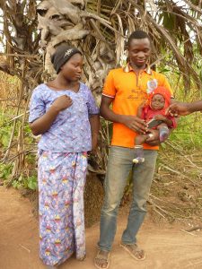 Woman and man standing, with him holding male child