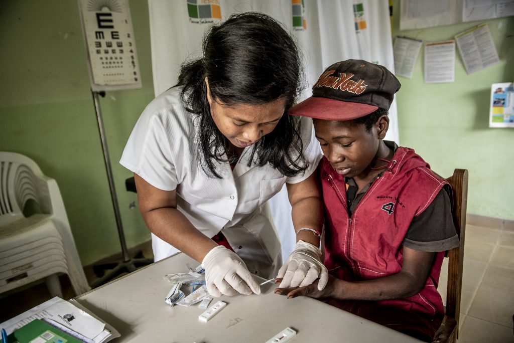 Nurse testing a young boy for malaria.