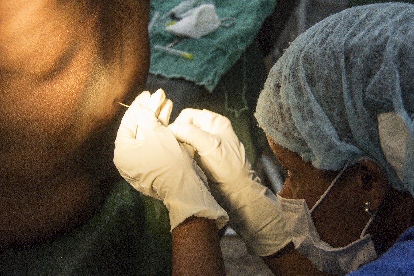 Person inserting a needle into lower back