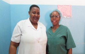 Two female nurses standing next to each other and smiling.