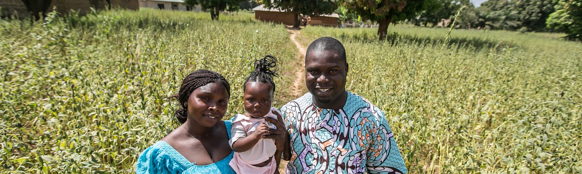 Peter Anmusku and wife Ruth  with daughter, Naomi, standing in field.