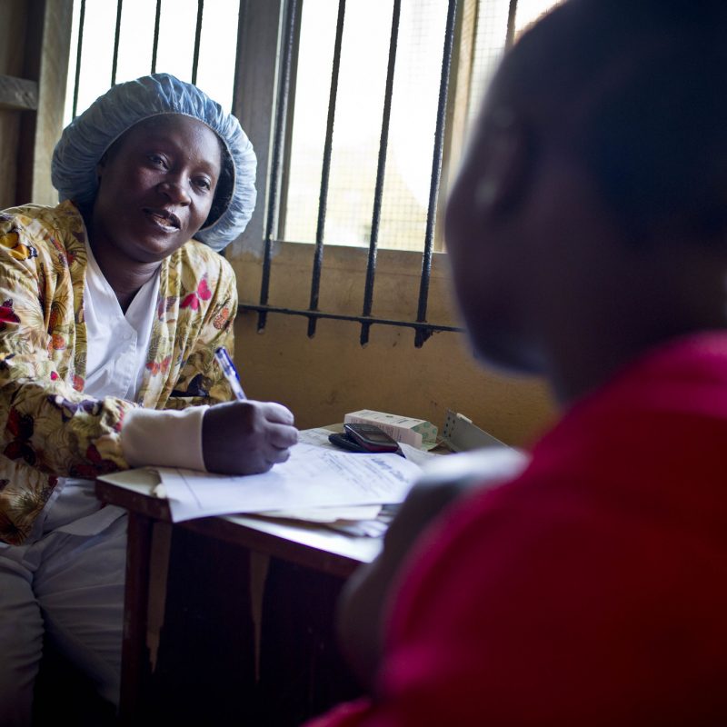 Nurse and client at a table as the nurse enters information in forms.