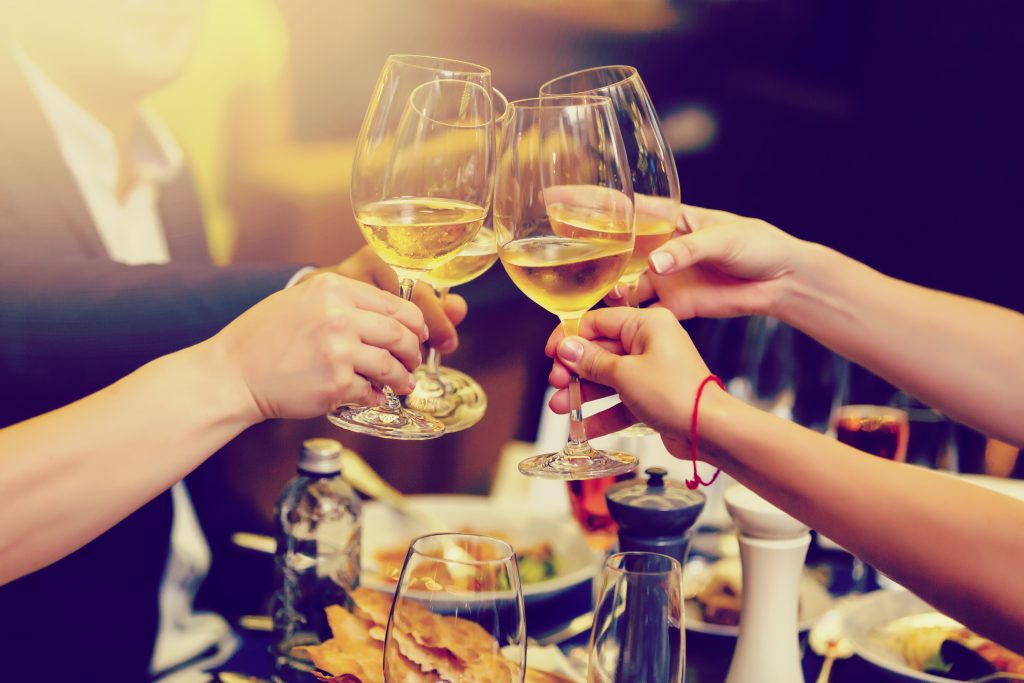 Photo of clinking glasses with white wine and toasting.