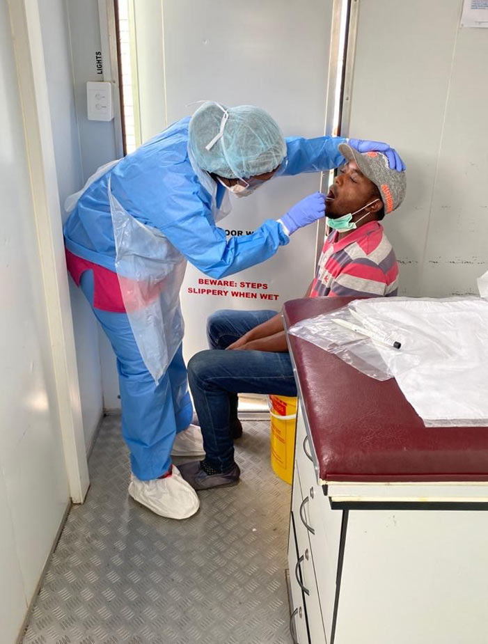 Patient being tested by nurse in protective gear.