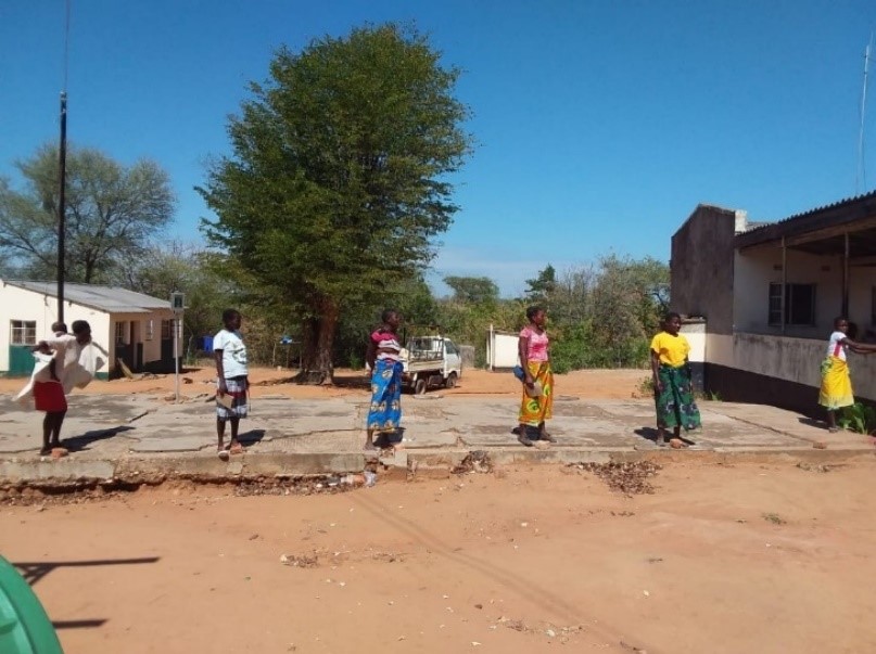 Women forming a socially distant queue outside a health facility